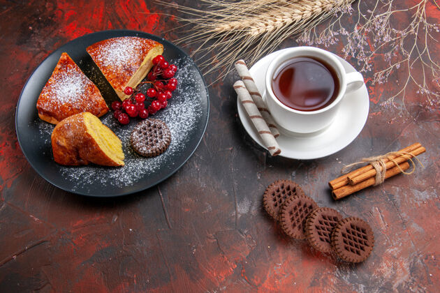 食物俯瞰美味的切片派与饼干和一杯茶在黑暗的桌子上甜甜的派蛋糕深色的茶碟