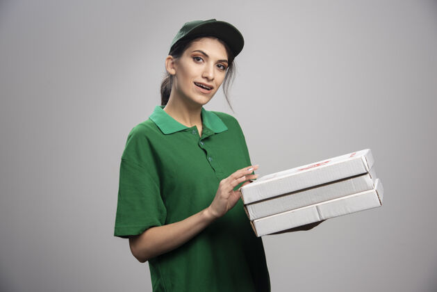女人年轻的女信使摆出披萨盒的姿势披萨咖啡雇员