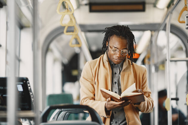 交通一个非洲裔美国人坐在城市公共汽车上一个穿棕色外套的人一个拿着笔记本的人公众城市非洲