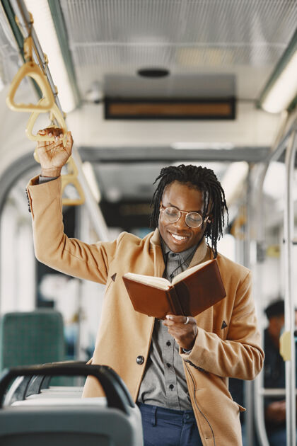 民族一个非洲裔美国人坐在城市公共汽车上一个穿棕色外套的人一个拿着笔记本的人黑人城市控股