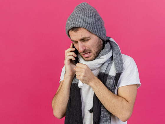 年轻咳嗽的年轻病患戴着带围巾的冬季帽子 在粉色背景上讲电话疾病咳嗽戴