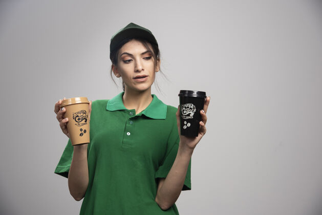 女孩穿着绿色制服的女送货员摆出美味咖啡的姿势快递工作事业