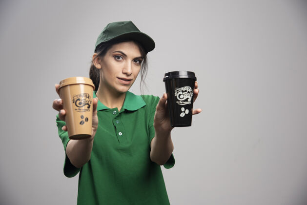 制服穿着绿色制服的女送货员摆出美味咖啡的姿势女人女孩事业