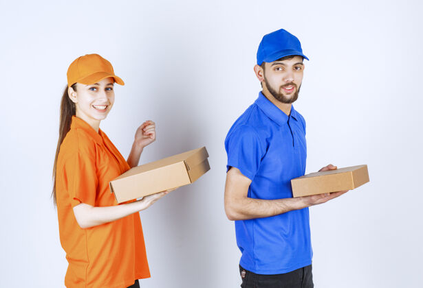 员工穿着蓝黄制服的男女快递员手里拿着纸板外卖盒和购物包女人男性呆在家里