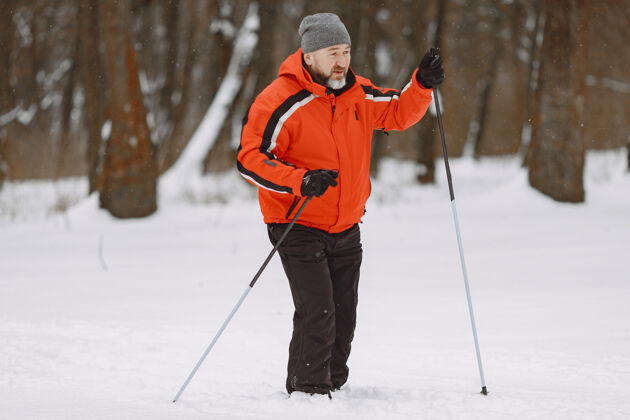 运动冬季公园里快乐的成熟男人高级运动服悠闲地在森林里跋涉老年人徒步旅行人