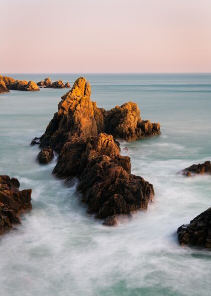 日出日落背景下岩石海滩的惊人镜头夏普光石头