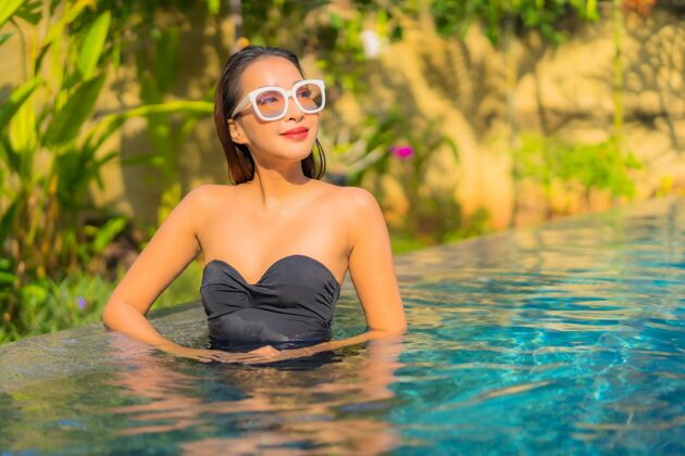 快乐美丽的亚洲年轻女子在游泳池里放松的画像酒店放松帽子