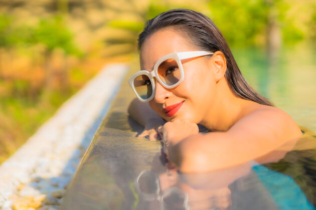 酒店美丽的亚洲年轻女子在游泳池里放松的画像假日游泳水