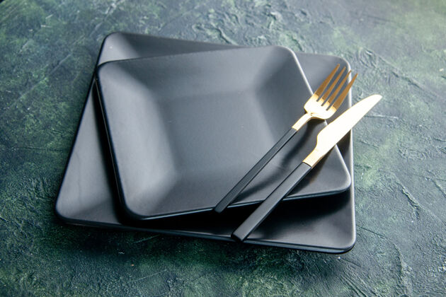 刀前视图黑色方形板 深蓝色背景上有金色的刀叉蓝色正餐厨房