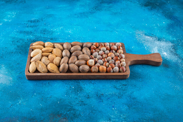 美味各种各样的坚果放在蓝色的板上坚果健康碗