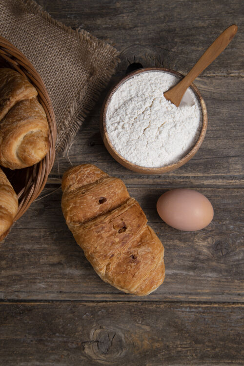 牛角包刚出炉的羊角面包 配上棕色的鸡蛋和面粉放在木桌上高质量的照片小面包面粉鸡肉