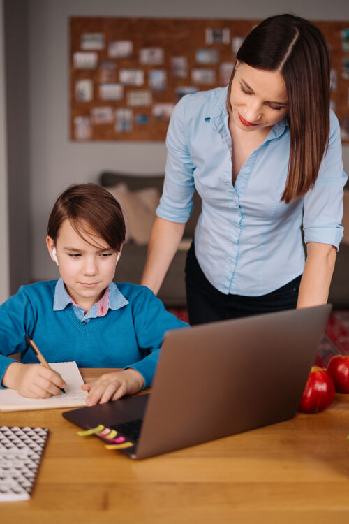 男孩一个未成年男孩用笔记本电脑和他妈妈旁边的老师打视频电话课程在线孩子