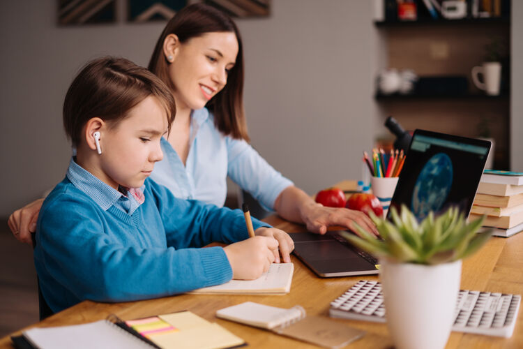 教育一个未成年男孩用笔记本电脑和他妈妈旁边的老师打视频电话女人学习老师