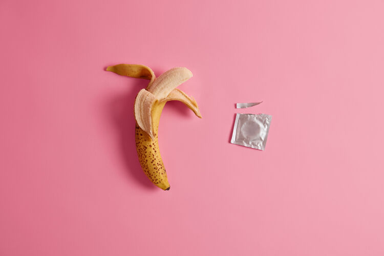 保护美味可口的高品质安全套适合你的心情粉红色背景的香蕉避孕药开胃的未去皮水果和橡胶制品 以增进亲密关系避孕方法安全理念预防风险安全