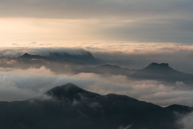 阳光日落时云层下的山脉的空中拍摄山峰天空岩石