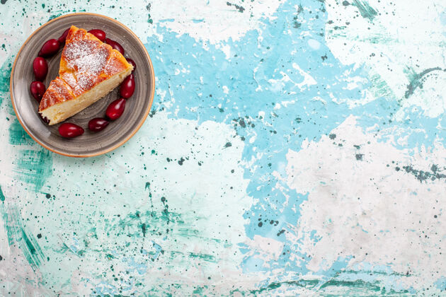 生的顶视图蛋糕片上有新鲜的红山茱萸在浅蓝色的背景上水果蛋糕烤派糖饼干甜浅蓝色蛋糕顶部