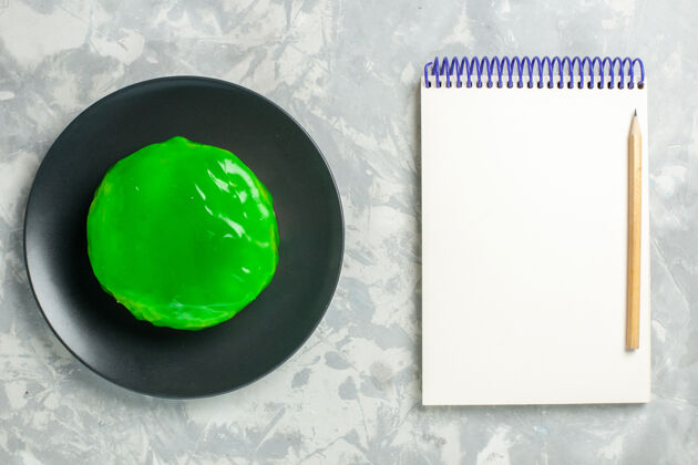 杯子俯视图绿色糖衣小蛋糕和白色表面的记事本蛋糕派饼干甜甜甜甜饼干空的生的视图