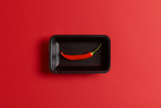 配料在市场上买的黑色托盘上放一整只长辣椒 红色背景上隔离开来为您的菜肴添加辛辣调味料食物和蔬菜概念从上面看热火辣膳食