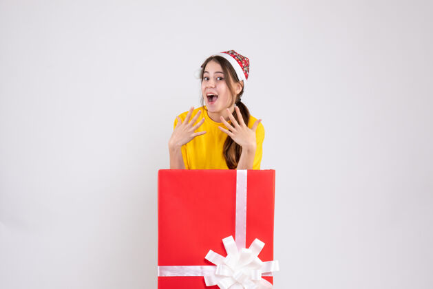 微笑前视图兴高采烈的女孩与圣诞礼物背后站着圣诞老人的帽子漂亮购物立场