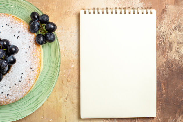 框架顶部特写视图蛋糕白色笔记本开胃蛋糕与葡萄蛋糕节日笔记本