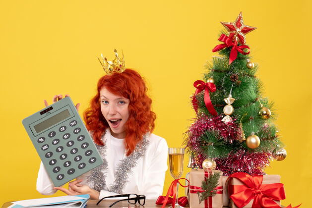 圣诞前视图女医生拿着计算器围着圣诞礼物和圣诞树情感节日年份