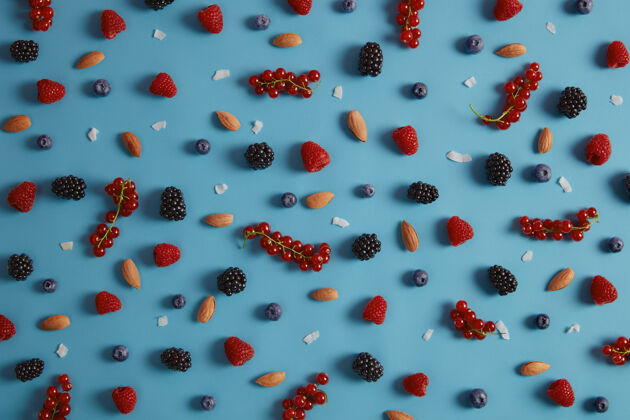 覆盆子混合各种新鲜浆果 包括覆盆子 蓝莓 黑莓 蓝背景红醋栗 杏仁和椰子片制作美味甜点的健康原料品种繁多混合配料黑莓