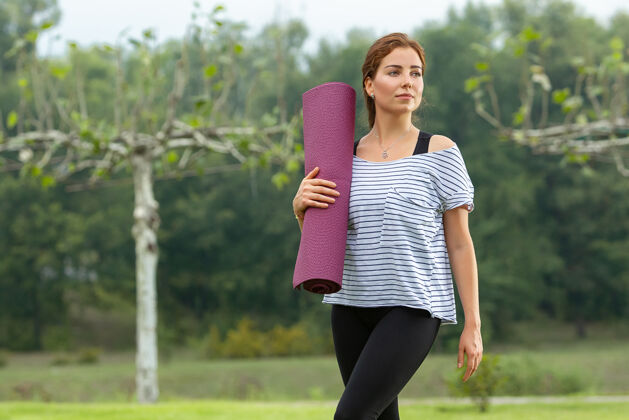 放松年轻漂亮的女人在绿色公园做瑜伽练习健康的生活方式和健身理念年轻锻炼女性