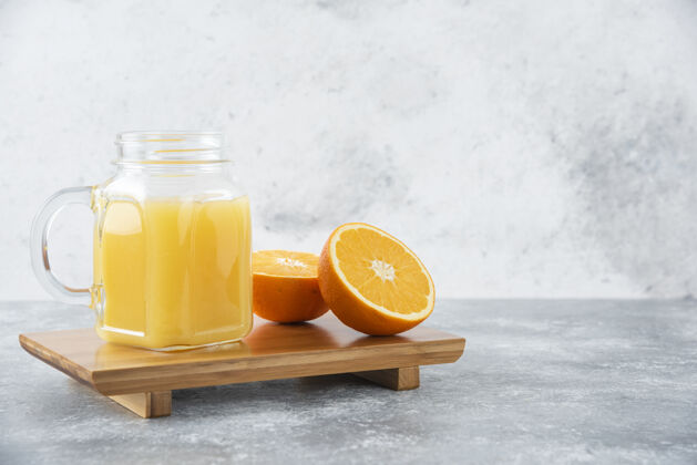 柑橘石桌上放着一杯果汁和新鲜的橙子果汁成熟异国情调