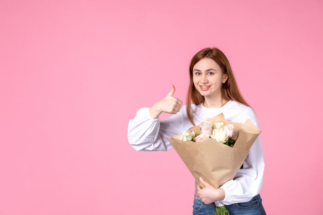 年轻的女性正面图：年轻女性 带花朵 作为女性节礼物 粉色背景 横向女性 三月女性 性感平等 玫瑰爱情花束人花