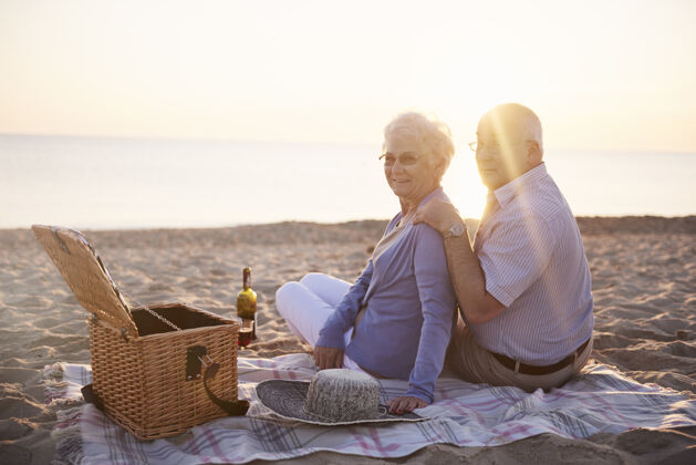 衰老过程日落时在海滩上野餐人际关系团聚浪漫