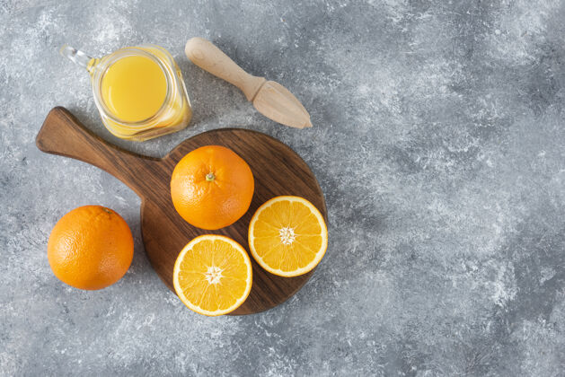 成熟石桌上放着一杯果汁和新鲜的橙子橙子多汁甜点