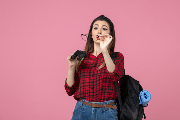 电话正面图穿红衬衫的年轻女性用望远镜在粉色地板上拍照模特肖像年轻女性地板