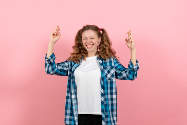 漂亮正面图：穿着格子衬衫的年轻女性在粉色背景上摆姿势 手指交叉 女性青年色彩情感童装模特成人年轻女性情绪