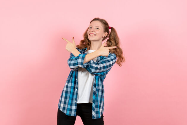 年轻女性正面图身着蓝色格子衬衫的年轻女性在粉色背景上摆姿势的女性儿童青年模特的色彩情感格子肖像漂亮