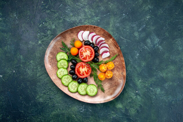 食物上图是新鲜切碎的蔬菜橄榄金橘在一个棕色的盘子里放在一张绿黑色的混色桌上传统托盘切碎的蔬菜
