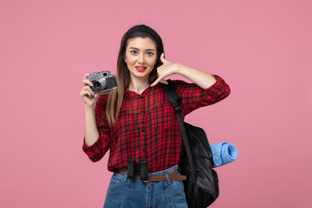 脸前视图年轻女性用相机在粉红色背景上拍照女性照片颜色漂亮人年轻女性