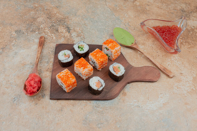 美味美味的寿司 鱼子酱 姜和瓦萨比放在木盘上姜汤匙寿司