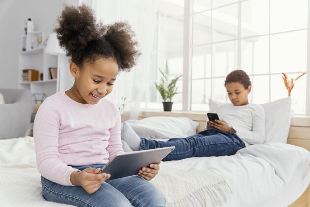 娱乐两个兄弟姐妹在家一起玩平板电脑和智能手机孩子设备娱乐