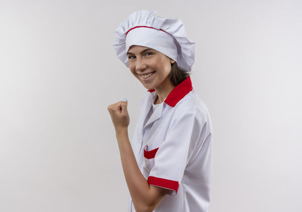 侧身身着厨师制服 面带微笑的白人年轻厨师女孩侧身站着 用拳头顶着白色 留着空白厨师拳头向上