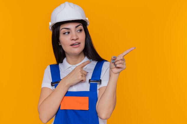 头盔穿着施工制服和安全帽的年轻建筑工人女人建筑制服