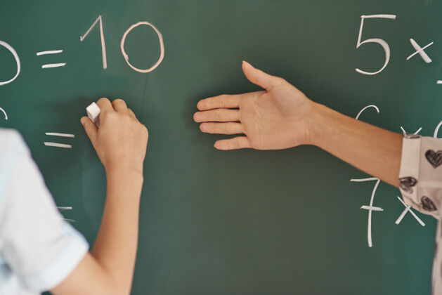 学生老师和她的学生在黑板旁边智力站立数学符号