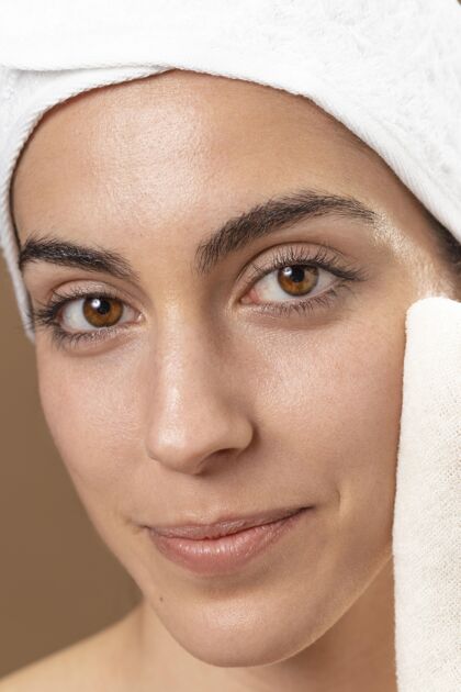 美容年轻女人用毛巾摸她的脸自我护理治疗眉毛