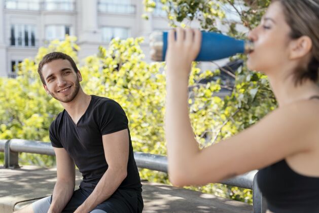 水瓶女人和男人在户外运动后喝水健身活动女人