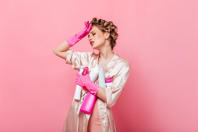 沟通女人洗完衣服很累 在粉红色的墙上摆出一副用洗涤剂擦的姿势年轻电话手套