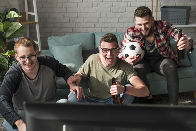 同伴前视图高跟男朋友看电视上的足球运动最好的朋友看电视