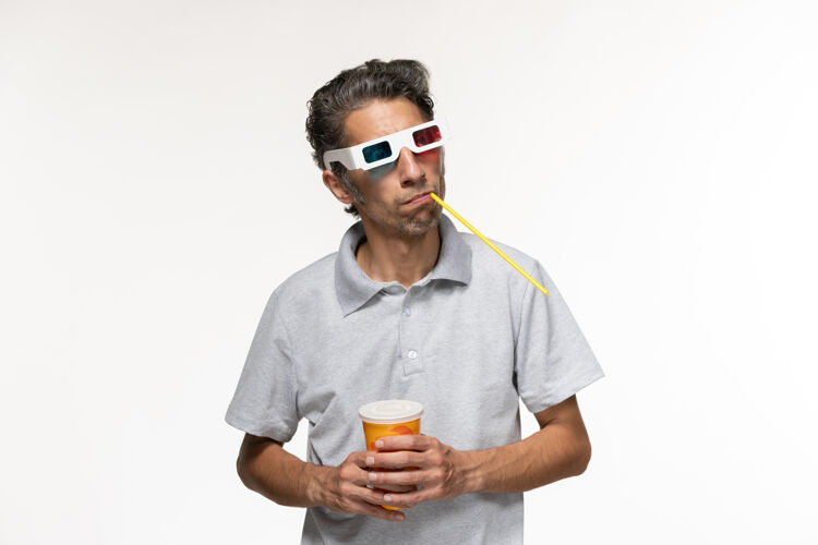 年轻男性正面图：年轻男性戴着d型太阳镜在白色表面喝苏打水看电影专业喝酒电影