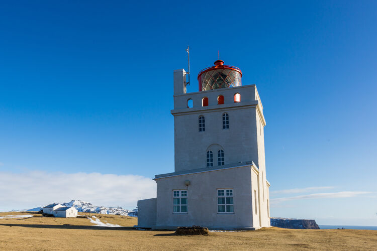 草地阳光下的戴尔霍雷灯塔和冰岛的蓝天北方天空寒冷