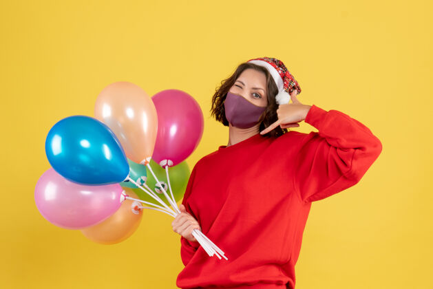 年轻女人黄色庆典派对上戴着面具手持气球的年轻女子气球女人面具