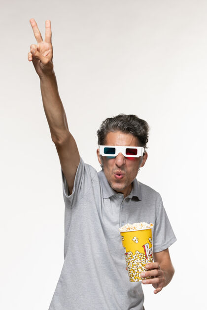 电影正面图年轻男性戴着d型太阳镜在白色表面吃爆米花衬衫爆米花前面