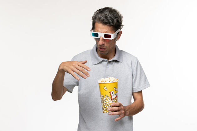 电影正面图年轻男性戴着d型太阳镜在浅白色表面吃爆米花孤独电影院爆米花